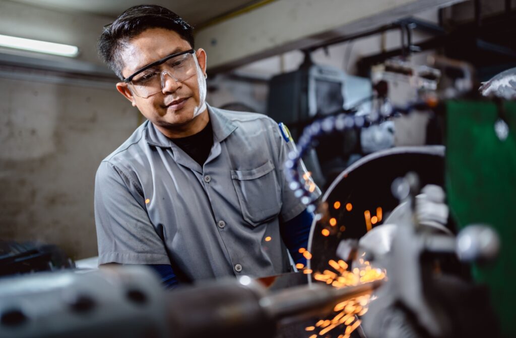 An industrial worker wears clear safety glasses that protect his eyes from flying sparks.