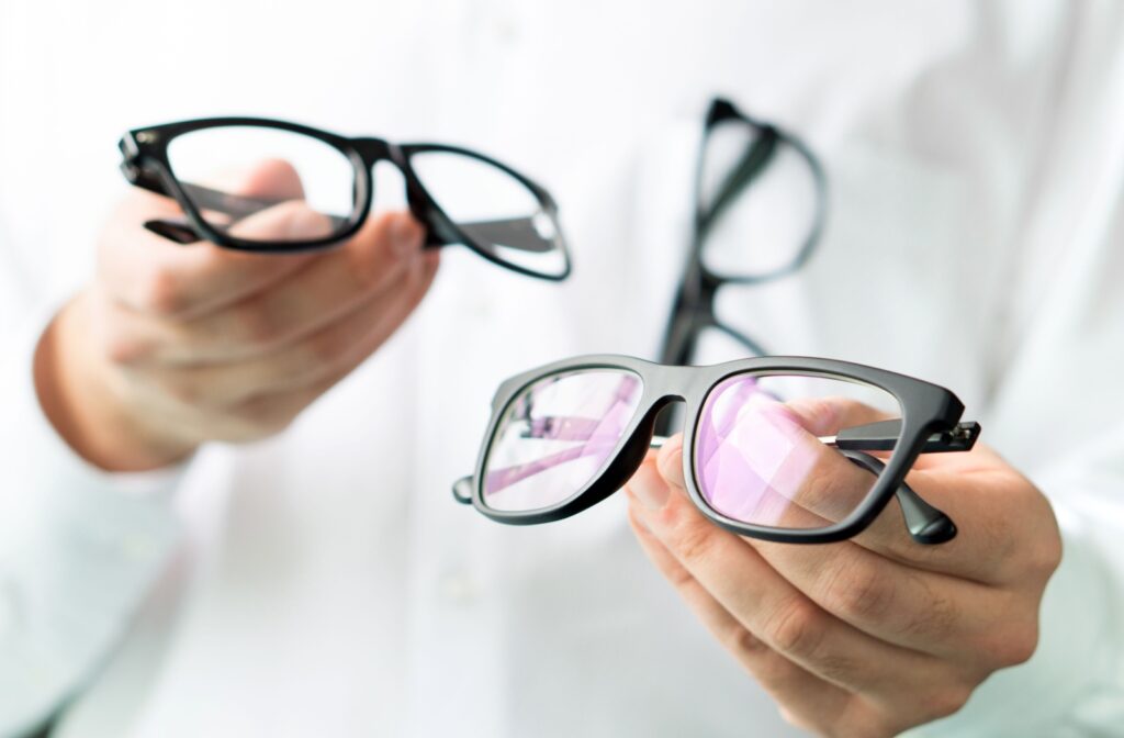 An out-of-frame optometrist comparing single-vision eyeglasses to a pair of transition multifocals.