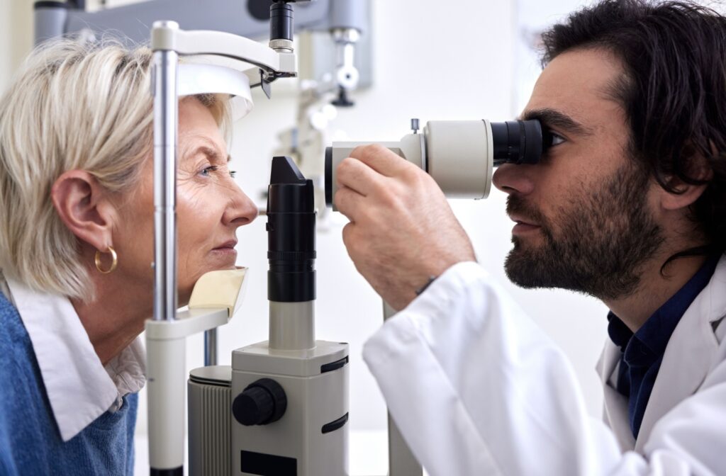 A side view of an optometrist examining the eyes of an older adult and looking for macular degeneration and glaucoma.