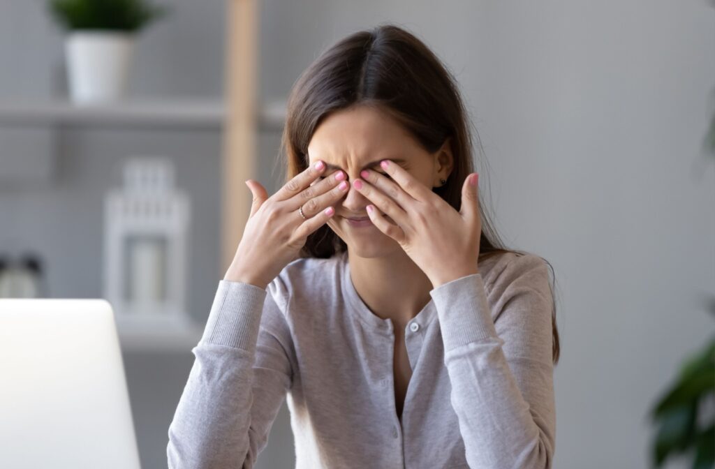 Young person rubbing their eyes, showing signs of dryness and strain, likely from prolonged screen time.