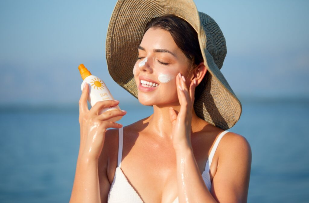 A person putting sunscreen on their face at the beach.