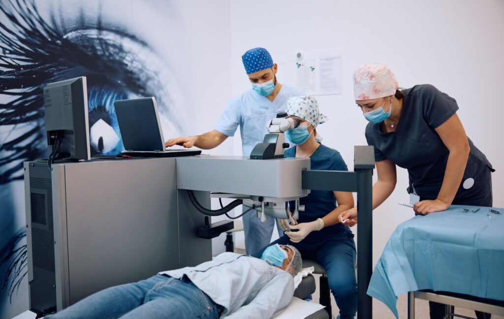 A person lies on their back as an ophthalmologist and their team prepare to perform cataract surgery on their patient's eye.