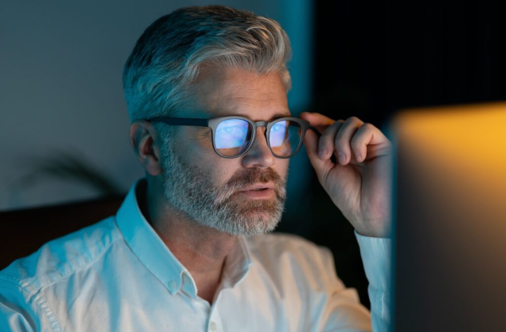 A man on a computer, wearing a pair of glasses with blue light filter lenses