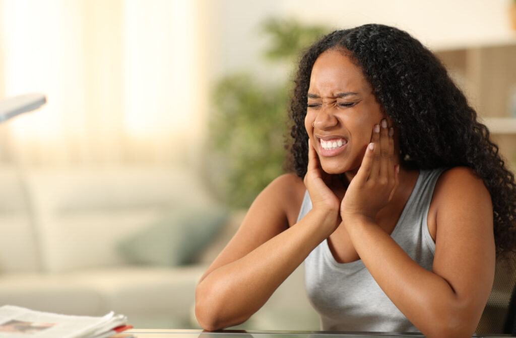 A person holding their jaw due to TMJ pain.