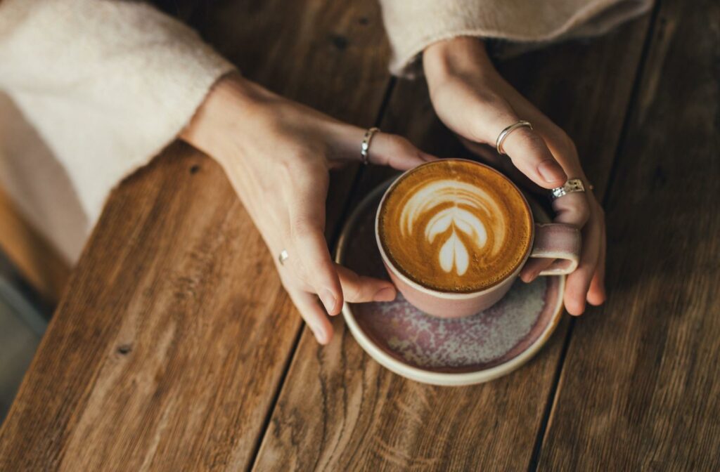 A birds eye view of a person's hands holding a cup of coffee.